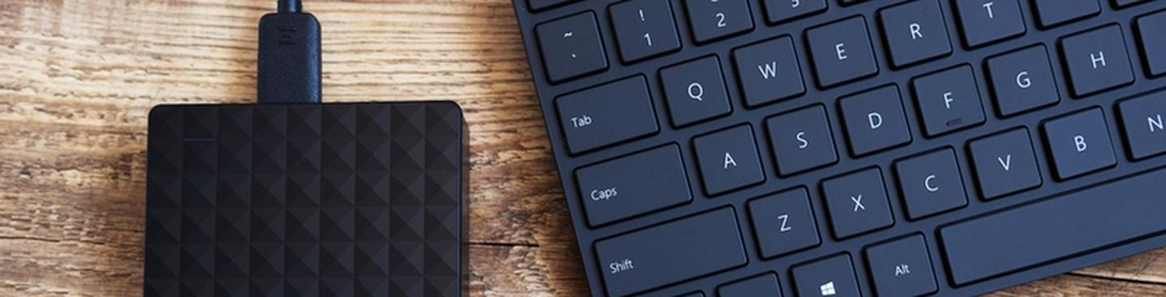 Disque dur externe posé sur un bureau avec câble USB