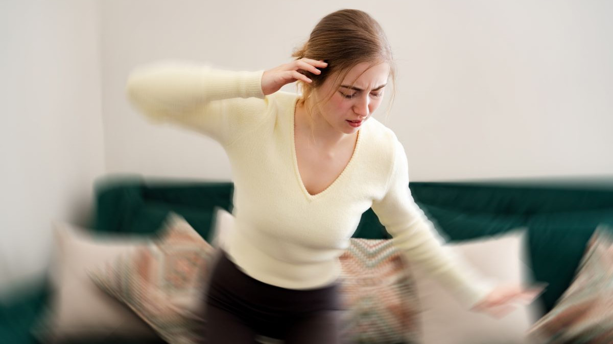 Personne assise, la main posée sur le front, ressentant une sensation de vertige et cherchant à retrouver son équilibre